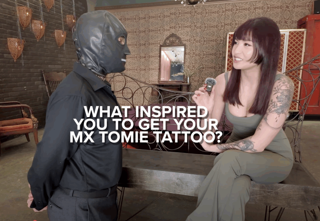 Mx Tomie asks submissive TomieDrone why he got his Mx Tomie tattoo.